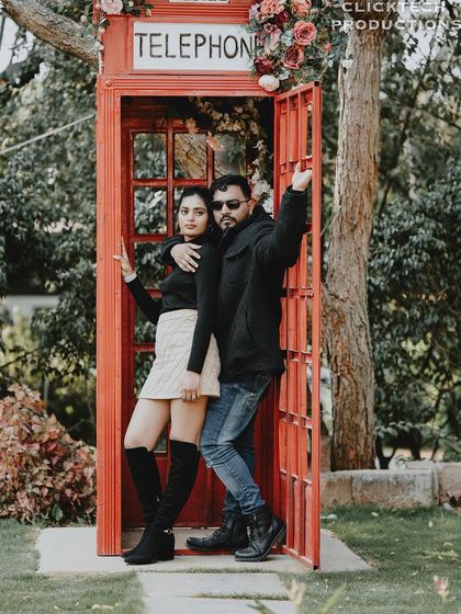 A duplicate of a fun and stylish pose of a couple in a red telephone booth.