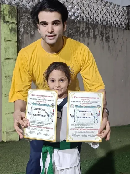 A student proudly displays two certificates of achievement from a recent championship. A fantastic result from a dedicated martial artist.