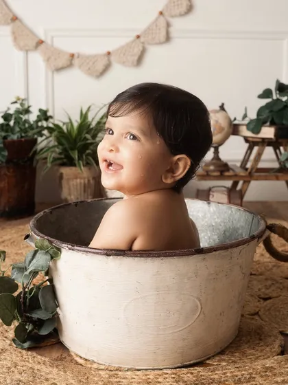 A happy baby looks off to the side, smiling, during his fun tub time. A beautiful profile shot filled with light and joy.