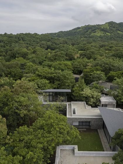 An aerial view of the 'Villa in a Grove', showing its relationship to the surrounding forest and the nearby hills. The design is a sensitive insertion into the landscape.