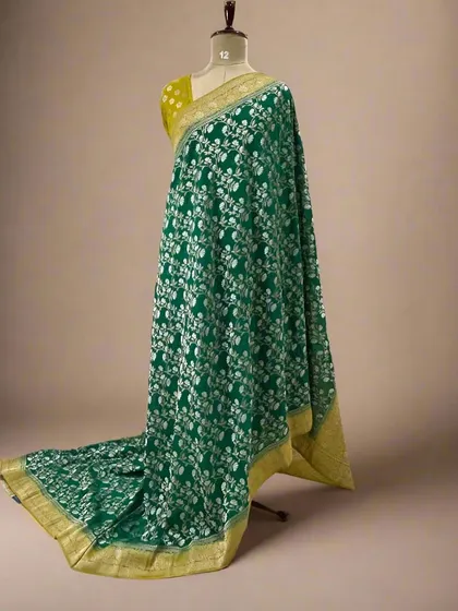 A rich green soft crepe saree with a full white floral jaal pattern and a yellow border.