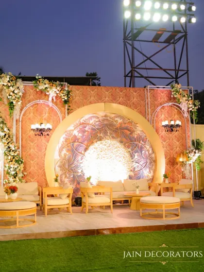 This outdoor reception stage combines intricate patterns with soft, romantic florals. The central backlit mandala creates a warm focal point, while elegant lounge seating invites guests to relax and enjoy the evening.