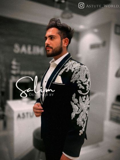 A side view of a client in a black tuxedo with heavy silver floral embroidery on the shoulder and sleeve. The detail in the threadwork is a testament to my team's craftsmanship.