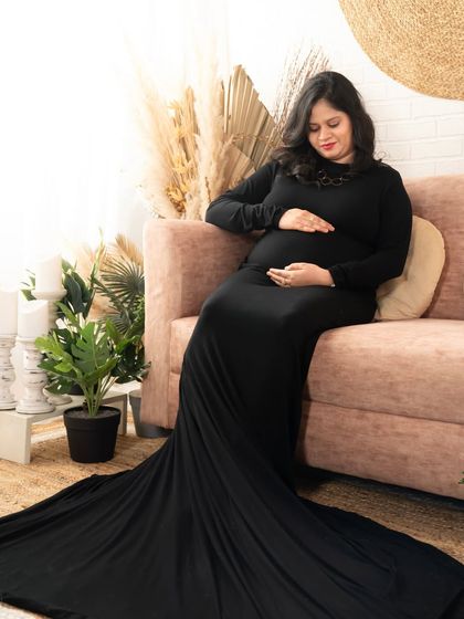 A serene portrait of the mom-to-be relaxing on the sofa. The long train of the black gown adds a touch of drama to this peaceful moment.