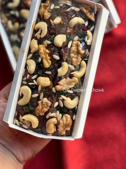 A close-up of the plum cake, showing how it's generously topped with cashews, walnuts, and other dry fruits.