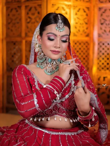 A seated portrait of a bride in a red lehenga with silver gota patti work, showcasing a Rajasthani-style look.