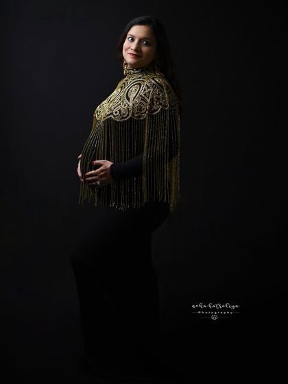 A classic portrait pose that lets the unique golden capelet and the mom-to-be's happy expression shine.