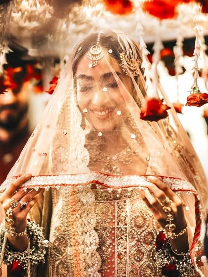 The bride's grand entrance, her face glowing under a traditional 'phoolon ki chadar'.