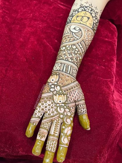 A close-up of one hand, showing the delicate lotus and peacock details.