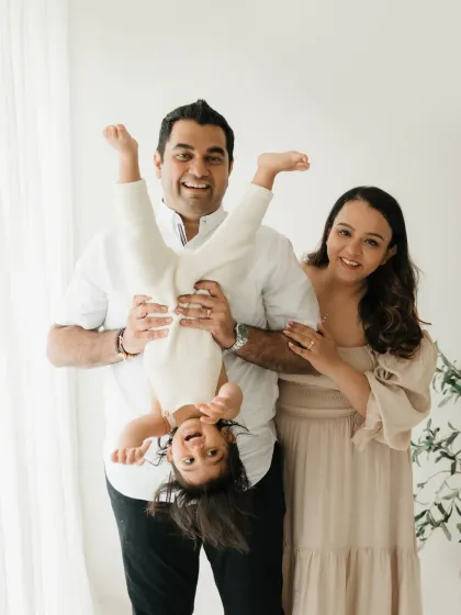 A father playfully holds his laughing child upside down during a fun family photoshoot in my studio. These lifestyle sessions are all about capturing the real, silly moments that define your family.