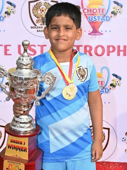 A young champion from our U7 team proudly holds the winner's trophy. We make football fun and rewarding for our little players.