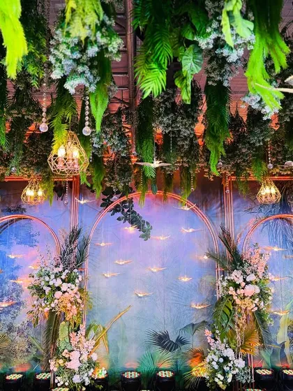 I brought a tropical rainforest to life for this Sangeet night. The decor features a lush canopy of hanging greenery, a hand-painted backdrop, and whimsical details like suspended birds to create an immersive, enchanting atmosphere.