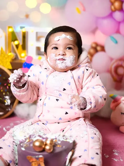 A candid moment from a first birthday cake smash, with a little frosting on her face. These are the authentic, funny memories that you will look back on and smile.