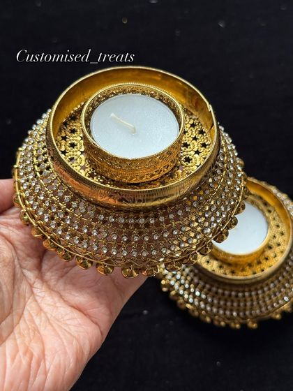 This antique-finish gold T-light holder is adorned with sparkling stones, perfect for creating a royal and luxurious atmosphere in your home.