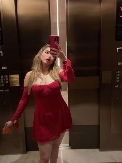 An elevator selfie in a cute red off-shoulder mini dress. This is a fun, relatable way to showcase a great party outfit.