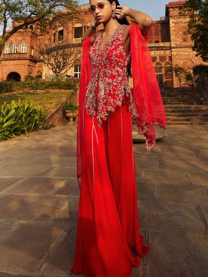 Red hot elegance. This vibrant red peplum top with intricate silver embroidery, paired with flowing palazzo pants, is designed for making a grand entrance.