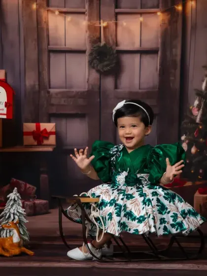 A happy toddler in a beautiful green dress enjoying our rustic Christmas setup.