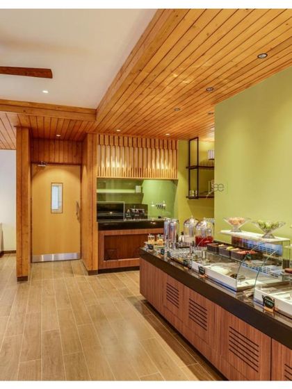 The buffet and service area of the restaurant uses a combination of wood and a soft green accent wall, continuing the nature-inspired theme of the resort.