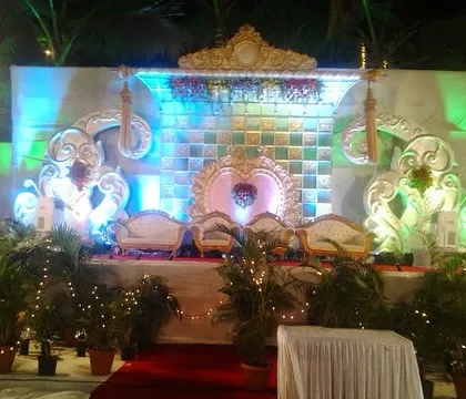 The final look of the fully lit reception stage. The intricate carvings on the backdrop and the elegant thrones for the couple are highlighted by the blue and green lighting, creating a royal feel.