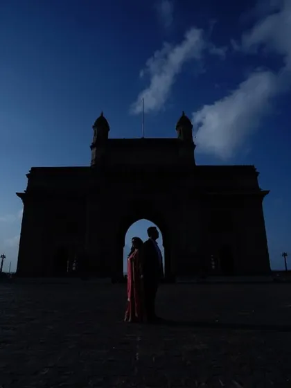A stunning silhouette of a couple against the Gateway of India at dusk, creating a dramatic and romantic image for their anniversary.