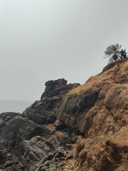 Trekkers climbing a rocky path along the coast, with the sea right beside them.