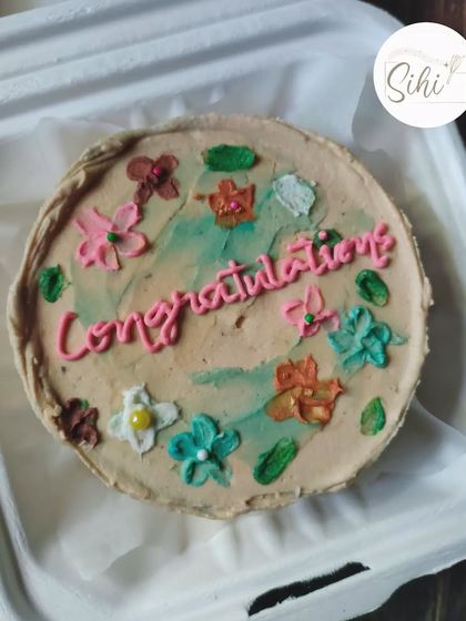 A lovely way to say congratulations. This bento cake features a rustic, earthy color palette with hand-piped flowers in various colors surrounding the celebratory message.