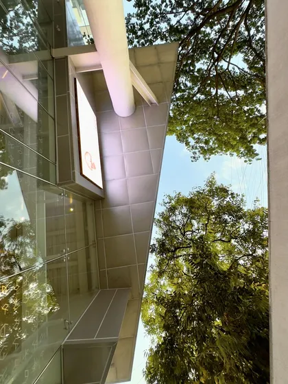 The view from the cafe courtyard looking up, where the building's reflective surfaces capture the sky and surrounding trees.