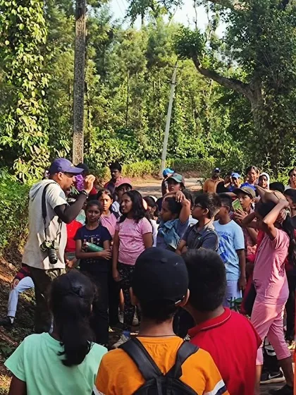 An instructor, a seasoned naturalist, points out interesting flora and fauna to a group of curious campers during a trek in Barapole.