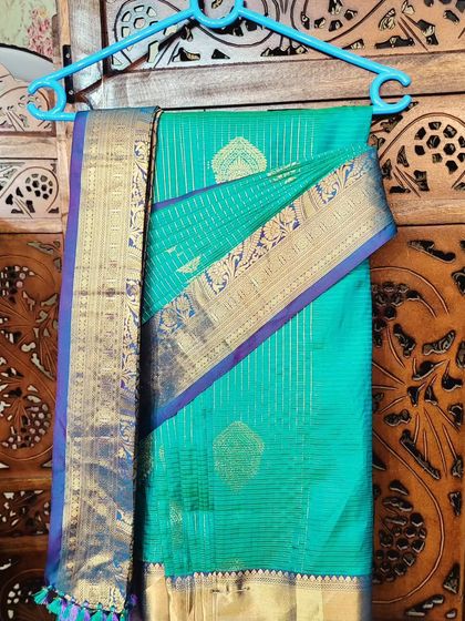 A pre-pleated teal silk saree on a hanger. This is a great way to organize your wardrobe and make wearing sarees a regular, easy affair.