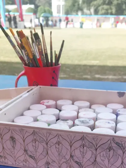 All the tools of the trade. A cup full of brushes and a box of paints, ready for a day of creativity at our outdoor carnival stall.