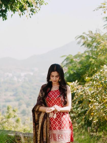 A close-up shot of the red kurta set, focusing on the intricate patterns and the traditional jhumka earrings.