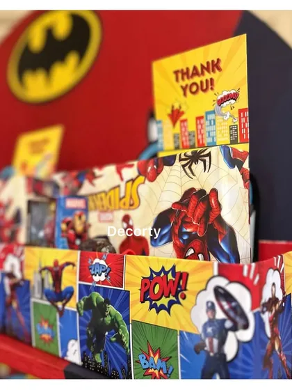 A close-up of the superhero-themed return gift station. The display features comic book graphics and the Batman logo.