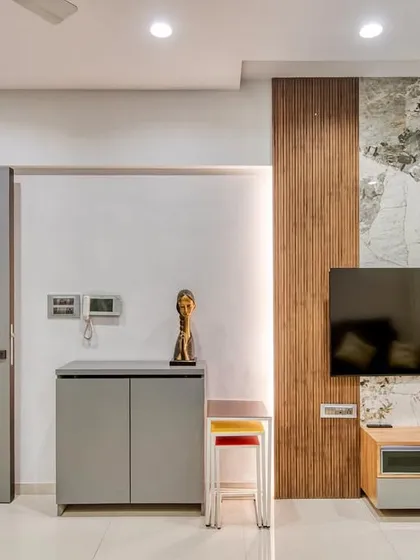 A wider view of the living room, showing the TV unit, shoe cabinet, and main door. We design every element to create a cohesive and harmonious interior.