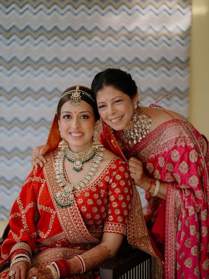 Another heartwarming mother-daughter portrait. The bride is in classic red, and her mother is in elegant pink, with both wearing makeup that is timeless and graceful.