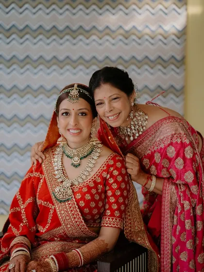 Another heartwarming mother-daughter portrait. The bride is in classic red, and her mother is in elegant pink, with both wearing makeup that is timeless and graceful.