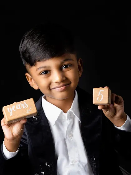 The same boy proudly holding up blocks that say "5 years" for his birthday photoshoot.