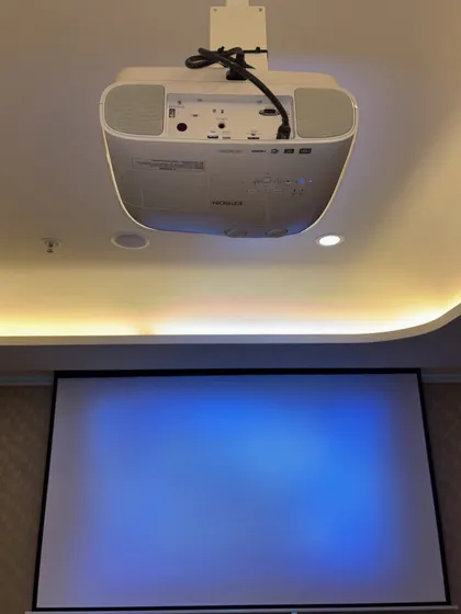 The Epson projector and motorized screen ready for a movie night. We ensure the projector is perfectly aligned with the screen for a sharp, cinematic image that fills the frame.