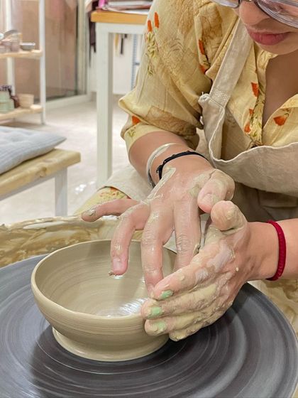 Shaping the inside of a bowl requires careful control. This student is using their fingers to define the curve and width of their creation.