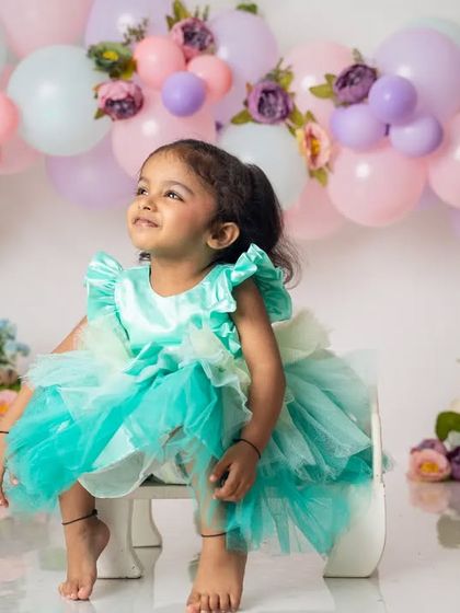 Looking up with a dreamy expression, this little girl is enjoying her second birthday photoshoot in a lovely seafoam green dress.