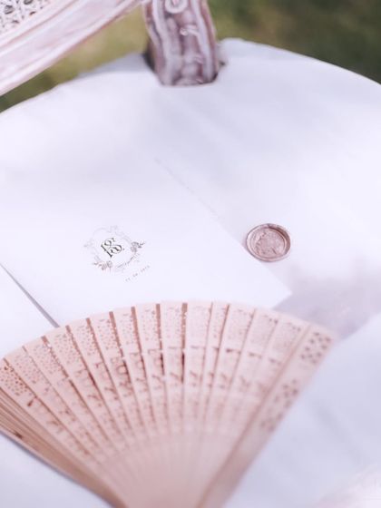 Personalized stationery details from the Bali wedding, including a custom wax seal and a delicate fan for guests. These thoughtful touches elevate the guest experience.