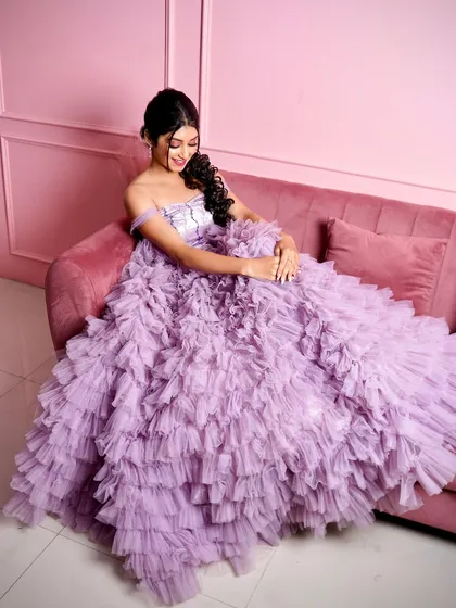 Feel like a princess in this lavender ruffle gown. It's one of my most popular rental pieces, shown here on our plush pink sofa against a matching pink wall, creating a dreamy, monochrome look.