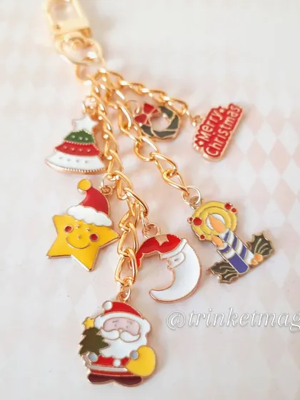 A close-up of the Christmas charm keychain, showing the detail on the Santa, star, moon, and Christmas tree enamel charms.
