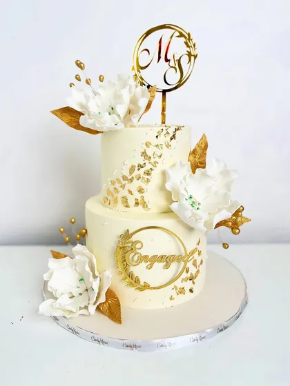 A full view of the white and gold engagement cake, complete with a custom monogram topper.