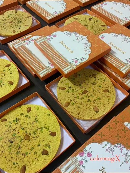 Introducing our gourmet Badaam Roti, a royal sweet delicacy. This traditional almond flatbread is presented in beautiful orange boxes with "Jai Mata Di" greetings, perfect for religious festivities.