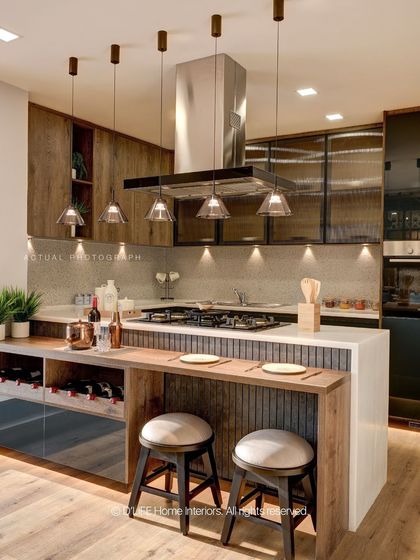 The island kitchen from our Madurai project combines rustic wood finishes with modern functionality, featuring a breakfast bar and stylish pendant lighting.