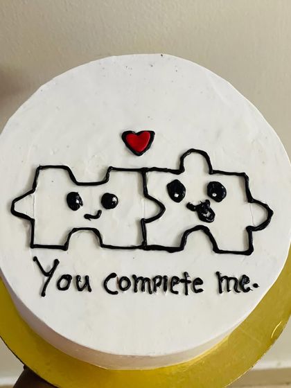 A cute puzzle-piece themed cake with the message "You complete me."