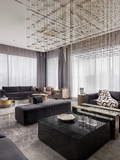 This view of the entertainment lounge highlights the spacious layout designed for large gatherings. We used multiple seating arrangements with plush velvet sofas and ottomans, all grounded by a large area rug and a striking geometric chandelier that defines the space.