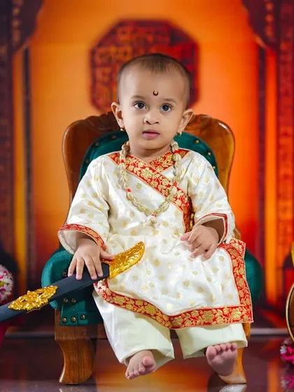 Honoring a legacy of courage with our Shivaji Maharaj themed photoshoot. Dressed in regal attire and holding a toy sword, this little warrior sits proudly on a miniature throne, creating a powerful and memorable portrait.
