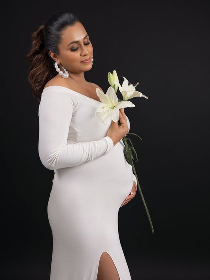 The addition of a simple white lily adds a touch of purity, grace, and symbolism to the portrait.