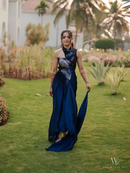 Walking through the gardens, she looks effortlessly chic in her modern gown. The makeup is designed to complement her high-fashion look with a touch of drama.